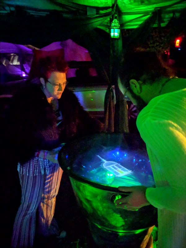 scrying mirror being visited by two people peering down into the visions in the bowl